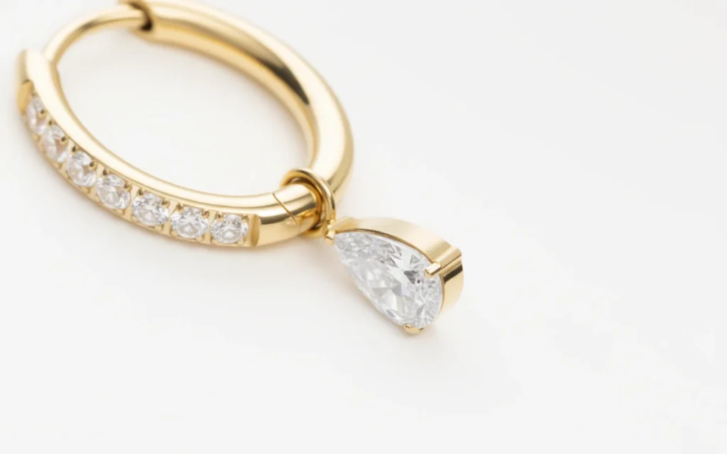 Gros plan sur boucle d’oreille en titane doré avec pendentif goutte en zircon