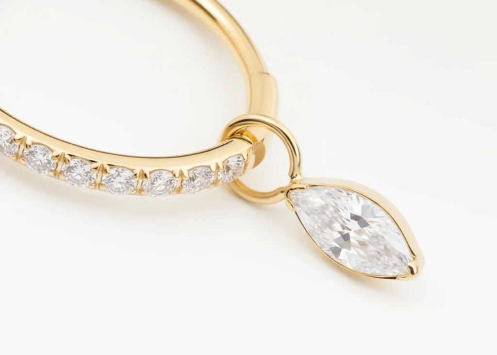 Piercing anneau doré serti de strass avec pendentif goutte, vue en gros plan détaillée