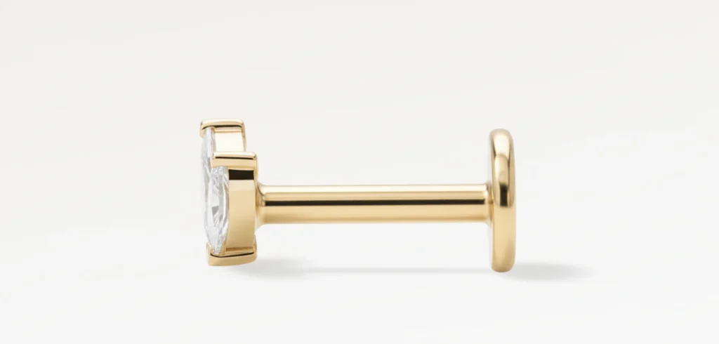 Gros plan sur piercing doré deux pétales, détails des zircons sertis visibles