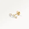 Piercing doré orné de trois zircons alignés, design élégant et lumineux