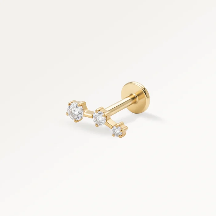 Piercing doré orné de trois zircons alignés, design élégant et lumineux